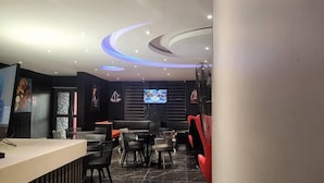 A modern restaurant with a black and red color scheme, featuring a TV screen, black chairs, and a counter. - Triple Tee Luxury Hotel (Lagos)