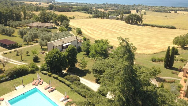 Une propriété résidentielle dotée d’une piscine, d’un court de tennis et offrant une vue sur un lac.