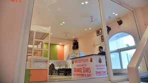 A reception area with a sign for Orange Stays, a bed, a desk, and a window.
