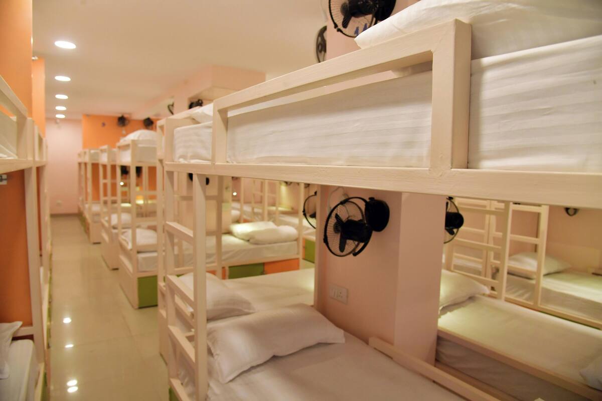 Diversos llits superposats en una habitació d'hotel amb un ventilador penjat a la paret.