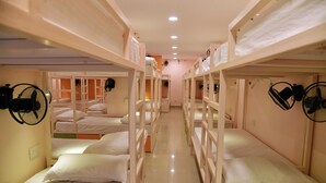 A corridor with bunk beds, each with a fan and white bedding.