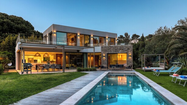 A modern two-story house with a swimming pool, outdoor seating, and a well-maintained garden.