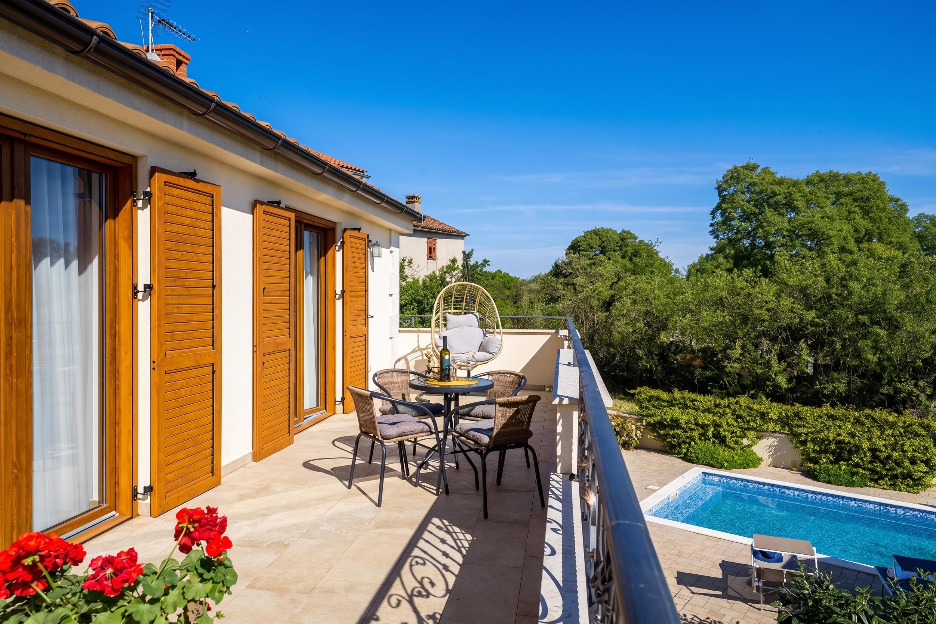 Un balcon avec une piscine, du mobilier d’extérieur et une vue sur la verdure environnante.
