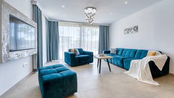 A modern living room with a blue sofa, matching ottoman, and a small coffee table.