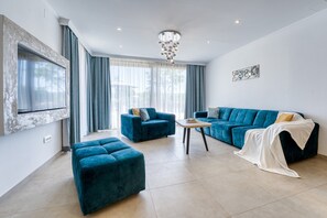 Uma sala de estar moderna com um sofá azul, um banquinho combinando e uma pequena mesa de centro.