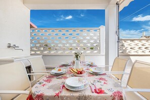 A dining table set with plates, cutlery, and a vase of flowers, surrounded by chairs, with a white fence and a clear sky in the background. - 3871 Villetta Anastasia by Barbarhouse (Manduria)
