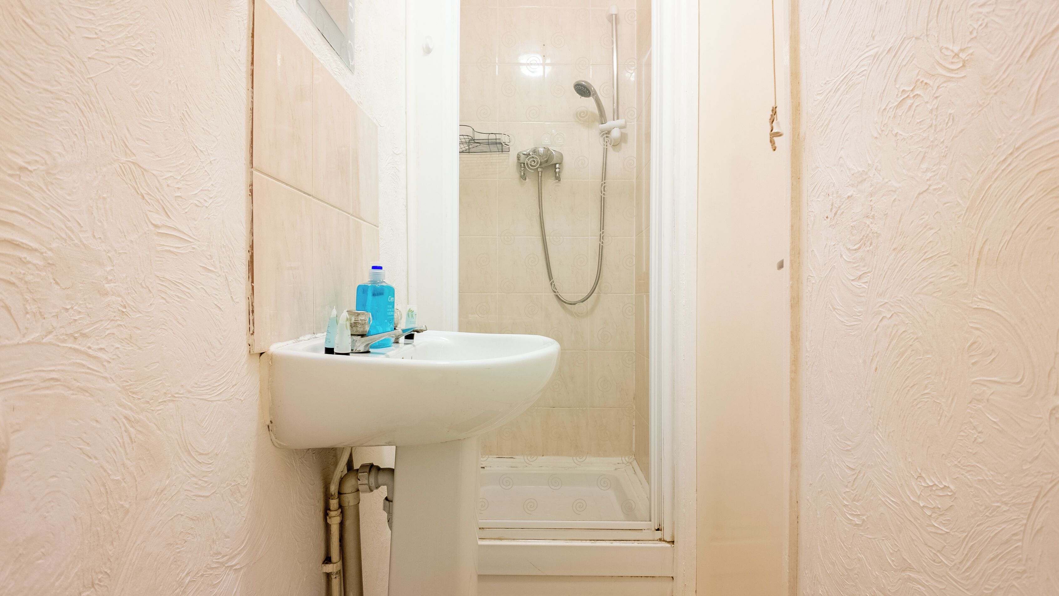 A bathroom with a white sink, a shower, and a toilet.
