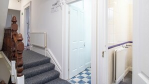 A staircase leading to a room with a checkered floor and a white door. - Pebbles Guest house (Southampton)
