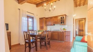 A kitchen with wooden cabinets, a dining table with chairs, and a chandelier.