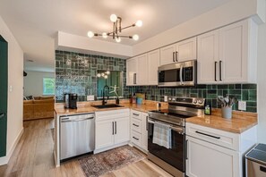 A modern kitchen with white cabinets, a stainless steel range, and a green backsplash.