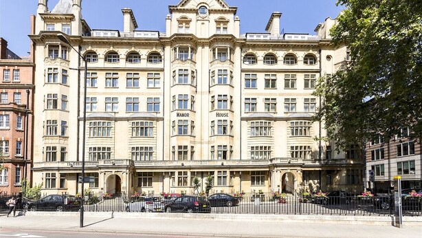 A large, historic building with multiple stories, featuring a prominent central entrance and symmetrical windows. - Sustainably Operated One-Bedroom Apartment in Central London (London)