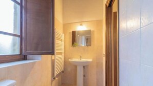 A small bathroom with a pedestal sink, a window with blinds, and a mirror above the sink. - Comfortable and essential for a carefree stay
 (Lazio)