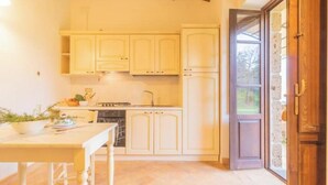 A kitchen with white cabinets, a stove, and a dining table with chairs. - Comfortable and essential for a carefree stay
 (Lazio)
