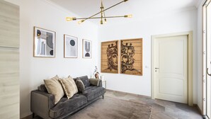 Una sala moderna con un sofá gris, obras de arte enmarcadas en la pared y una araña.