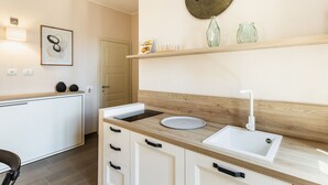 A modern kitchen with a wooden countertop, white cabinets, a sink, and a round wall clock.