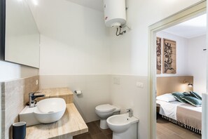 A modern bathroom with a large mirror, a sink, a toilet, and a bidet.