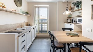 A modern kitchen with white cabinetry, a wooden dining table, and a pendant light.