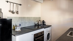 Een kleine keuken met een wasmachine, een koffiezetapparaat en een magnetron.