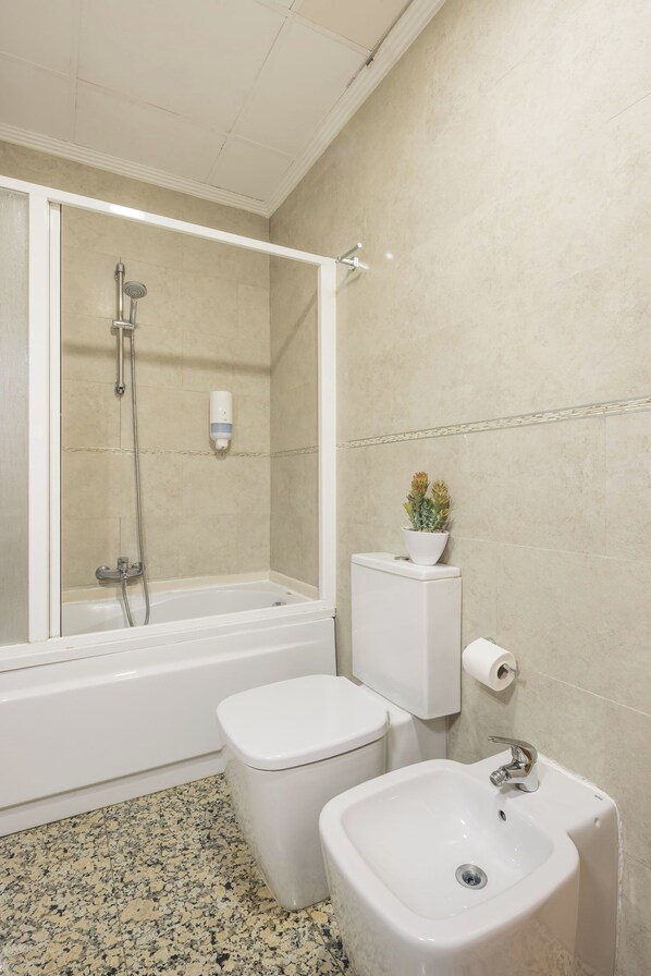 Un baño con ducha, inodoro, bidé y lavamanos.