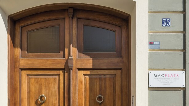 A wooden double door with a metal handle, a number '35' sign, and a 'MACFLATS' sign on the adjacent wall. - Macflats Valencia Puerto (Valencia)