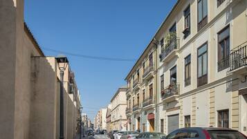 Una calle bordeada de coches aparcados y edificios con balcones.