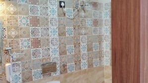 A bathroom with a toilet, a hand dryer, and a wall-mounted heater. - Madhav Residency (Mathura)