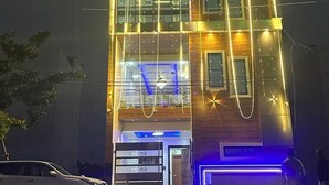 A multi-story building with a modern design, featuring a prominent entrance with glass doors and a blue-lit area near the ground floor. - Madhav Residency (Mathura)