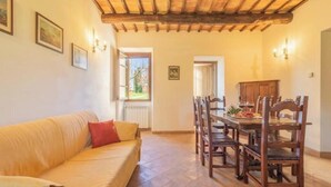 A cozy living room with a wooden ceiling, a sofa with cushions, a dining table with chairs, and a view of the outdoors. - Comfort and attention to detail for a stay in the country
 (Lazio)