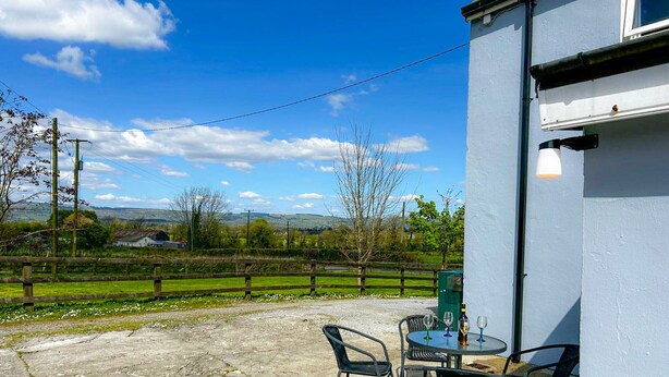 A patio with outdoor seating and a view of the countryside. - Lisheenbawn Farmhouse Farranfore (Castleisland)