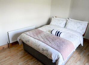 Une chambre à coucher avec un lit, un radiateur et un plancher en bois.