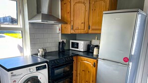 A compact kitchen with a washing machine, stove, microwave, and refrigerator. - Lisheenbawn Farmhouse Farranfore (Castleisland)