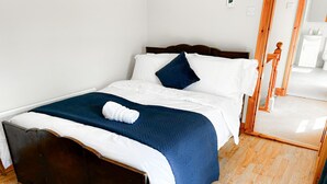 A neatly made bed with white and blue bedding, a wooden headboard, and a wooden floor. - Lisheenbawn Farmhouse Farranfore (Castleisland)