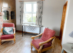 Une pièce comprenant deux fauteuils en bois, une petite table et une fenêtre avec des rideaux.