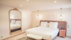Ein Schlafzimmer mit einem großen Bett, einer Bank, einem Nachttisch, einem Spiegel und zwei Wandleuchten.