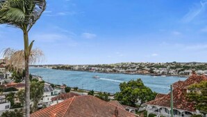A coastal town with a view of the sea, buildings with red-tiled roofs, and a palm tree. - Brisbane Hamilton Hill With Panorama View (Hamilton)