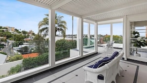 A spacious balcony with large windows, a white wicker sofa, and a clear view of the surrounding cityscape. - Brisbane Hamilton Hill With Panorama View (Hamilton)