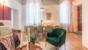 A modern living room with a sofa, a green armchair, a dining table with chairs, and a kitchen area in the background. - Wine Apartments Florence Prosecco (Firenze)