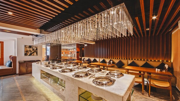 Un buffet avec un comptoir en marbre, de nombreux plats de service et un luminaire suspendu.