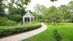 Un jardin agrémenté d’un belvédère, d’un chemin de pierres et d’une végétation luxuriante.
