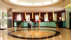 Un hall d’hôtel à la conception circulaire, avec un comptoir d’accueil au centre et un sol poli.
