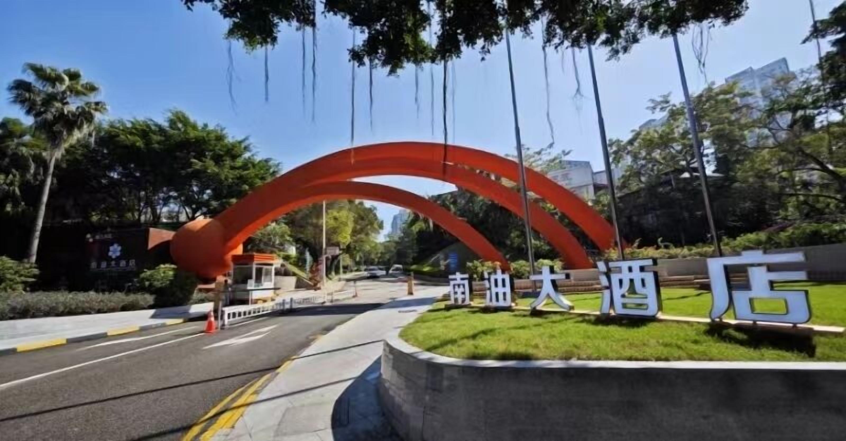 Entrada de hotel con un gran arco rojo y un cartel con caracteres chinos.