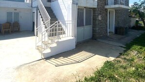 Une maison à deux étages avec un balcon, un escalier et un petit jardin.