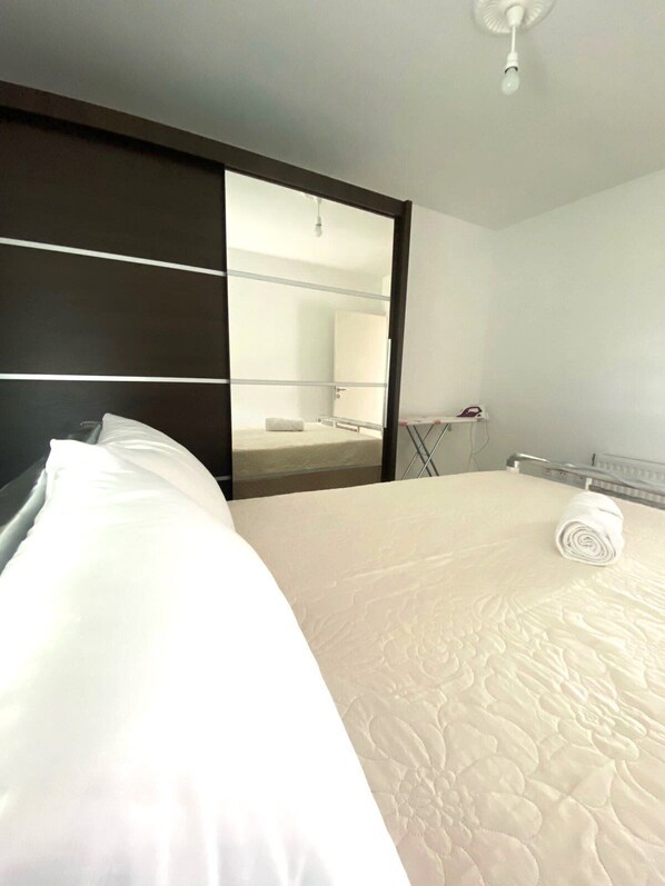 Une chambre d’hôtel avec un grand lit, un miroir, un ventilateur de plafond et un radiateur.