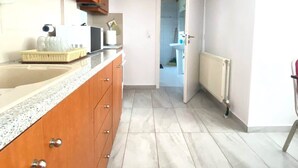 Une cuisine avec des meubles en bois, un plan de travail en granit et un sol carrelé.