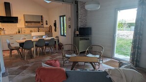 Un soggiorno moderno con pavimento in pietra, un divano, un tavolino da caffè e un'area pranzo con sedie e tavolo.