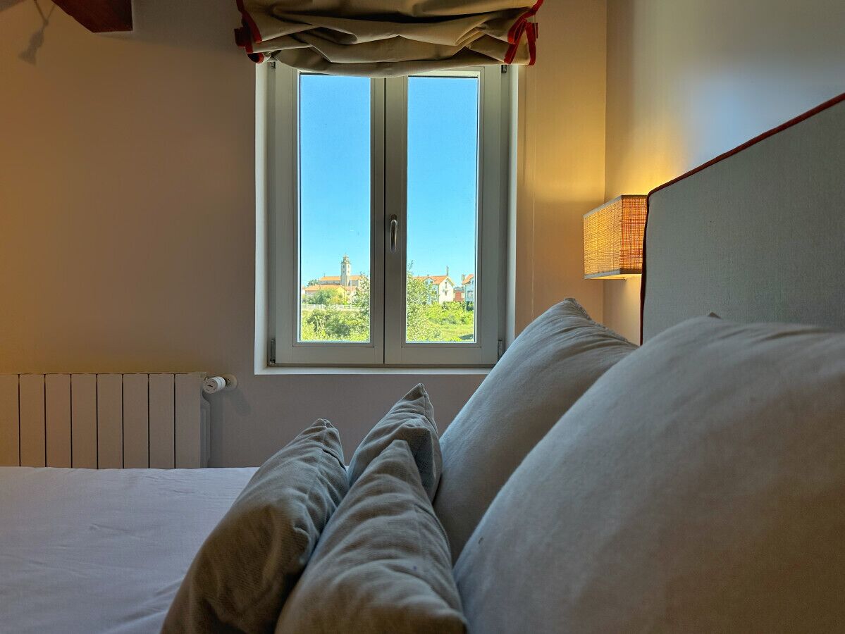 Un lit donnant sur un immeuble, vu à travers une fenêtre.
