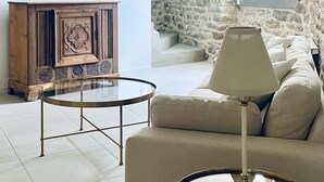 A living room with a sofa, two round tables, a lamp, and a wooden cabinet. - Step into French history at Le Bastion, Pouzols-Minervois, southern France. (Pouzols-Minervois)