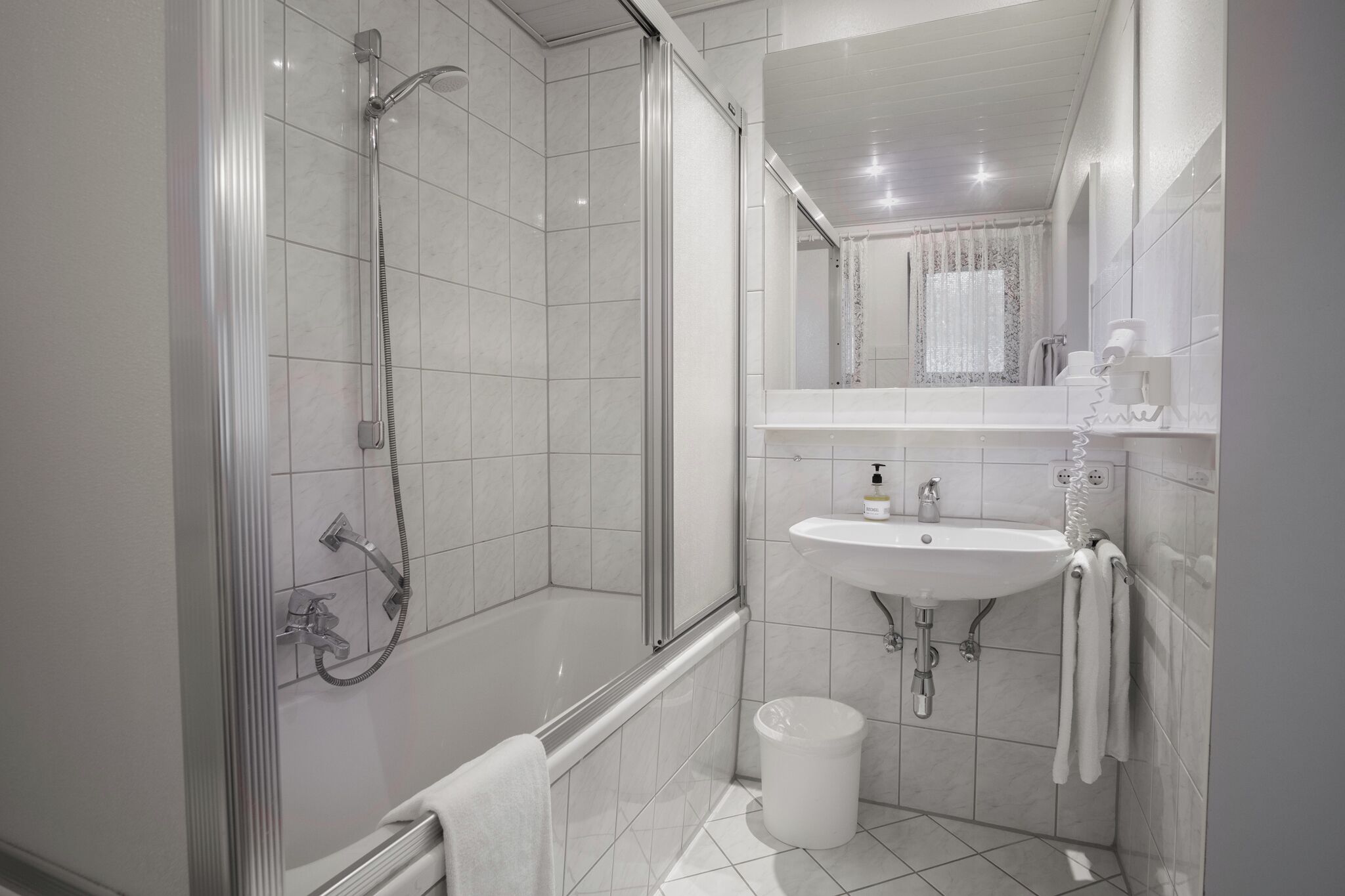 Un baño moderno con ducha, bañera, lavamanos y espejo.