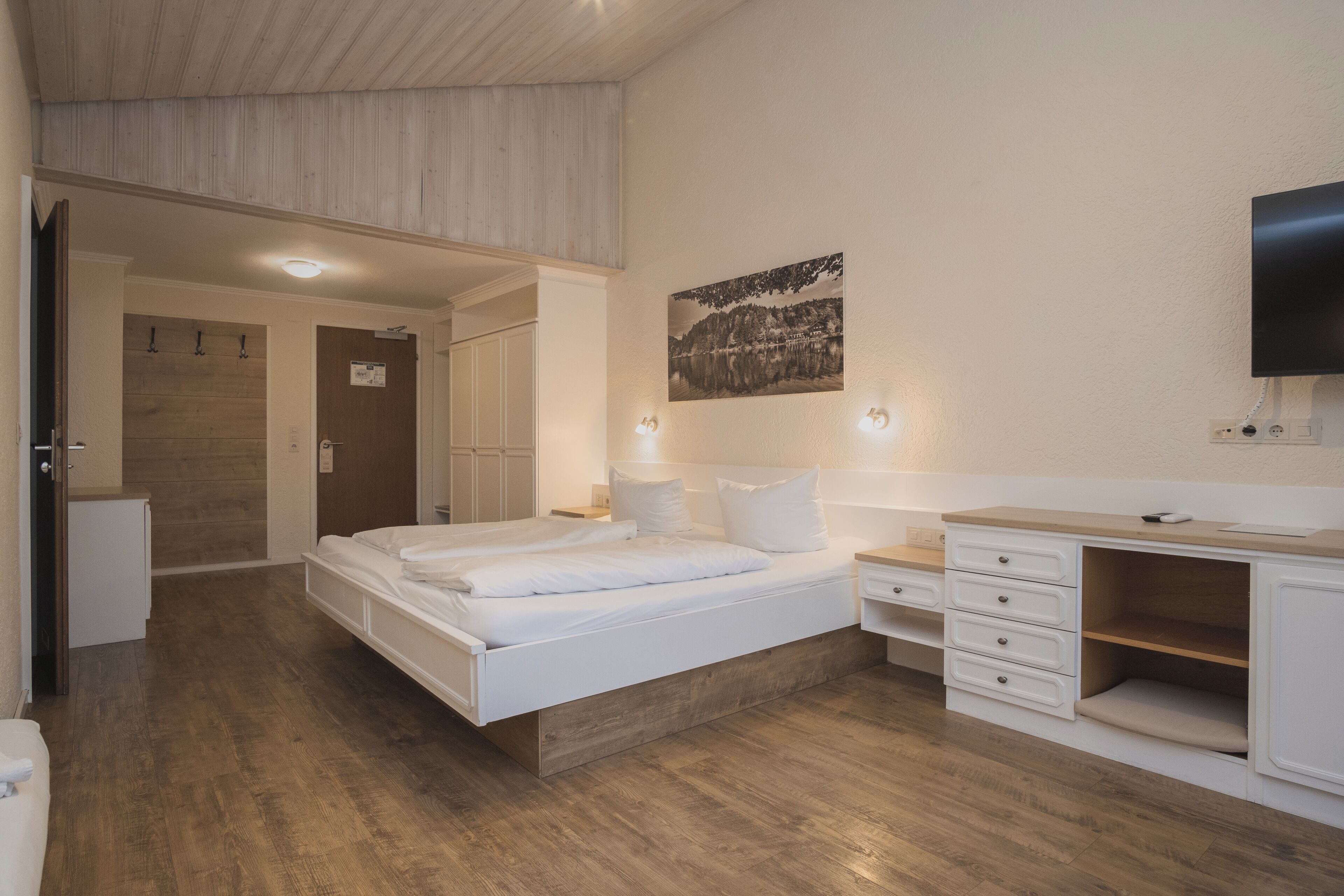 Une chambre à coucher avec un lit, des tables de chevet, une télévision et un tableau au mur.