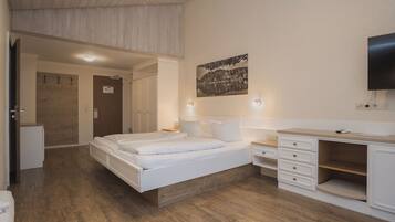 A bedroom with a bed, bedside tables, a TV, and a painting on the wall.